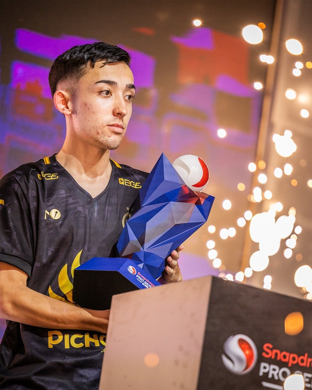 EA FC Mobile competition winner holding the Snapdragon Pro Series trophy in São Paulo